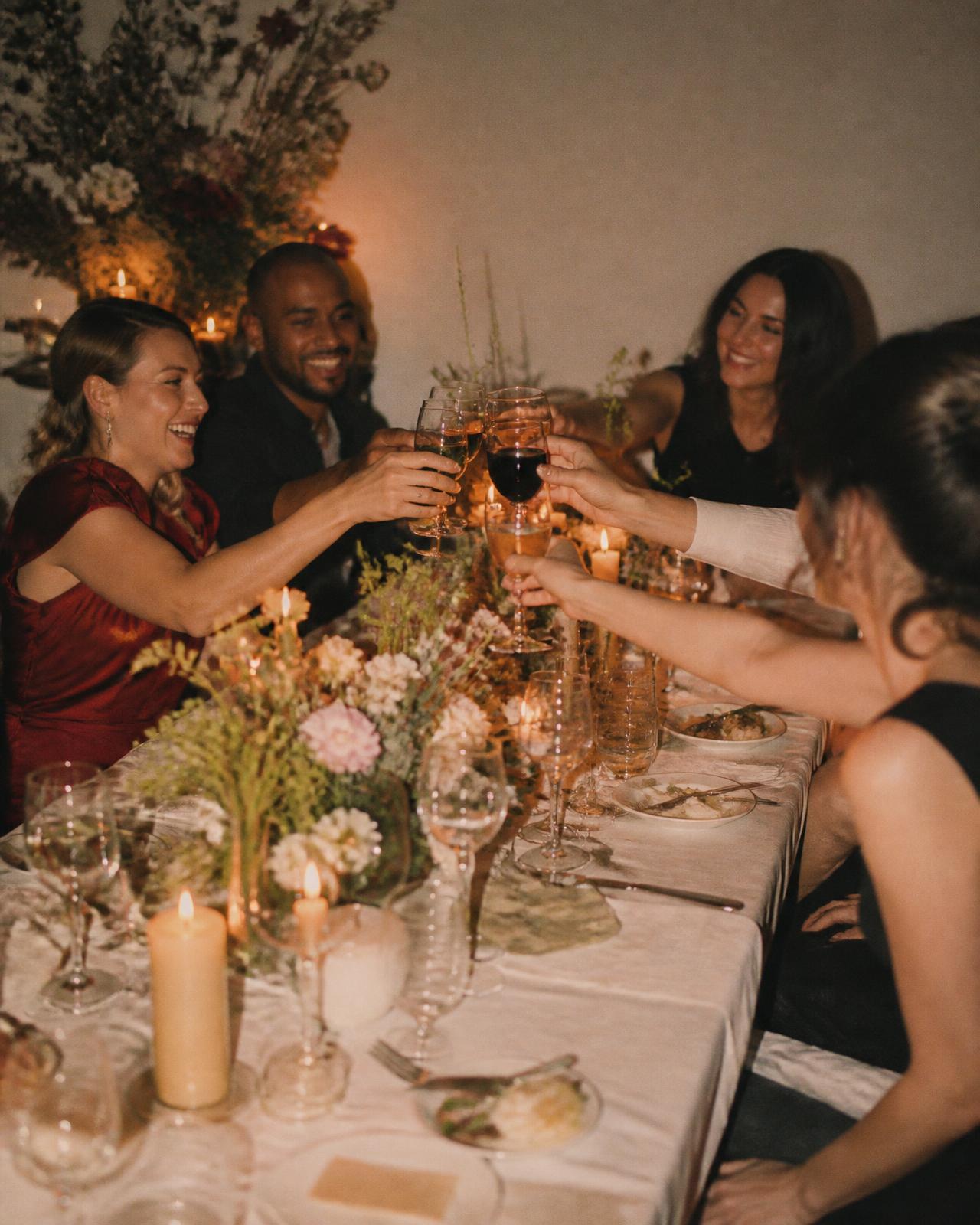 Friends raising their glasses around a candlelit dinner table at an intimate birthday