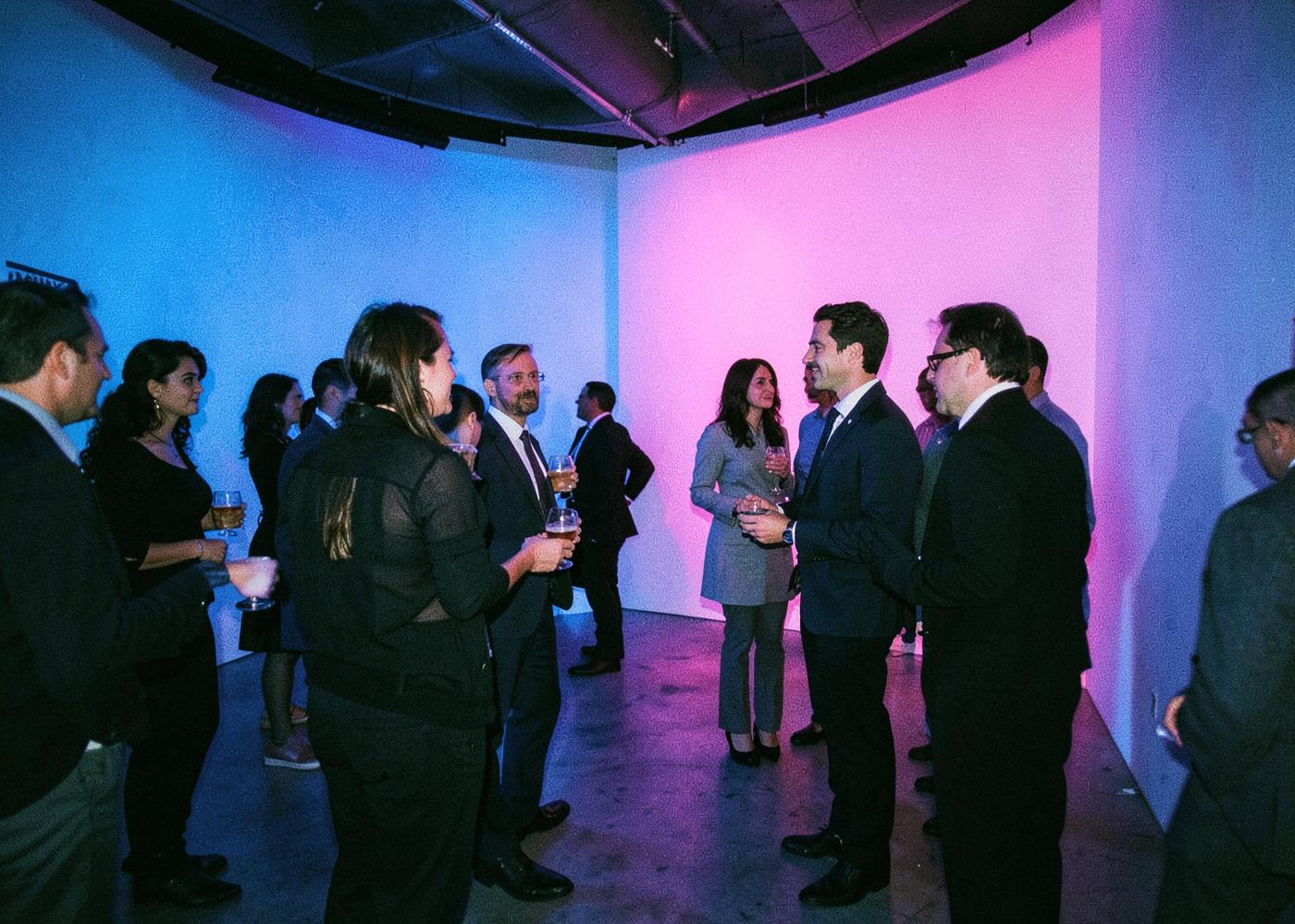 Guests talking with drinks in hand inside a contemporary, colourfully lit brand activation
